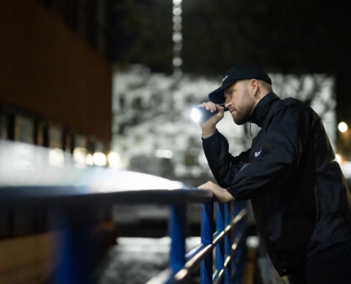 Security guard shining flashlight down ledge